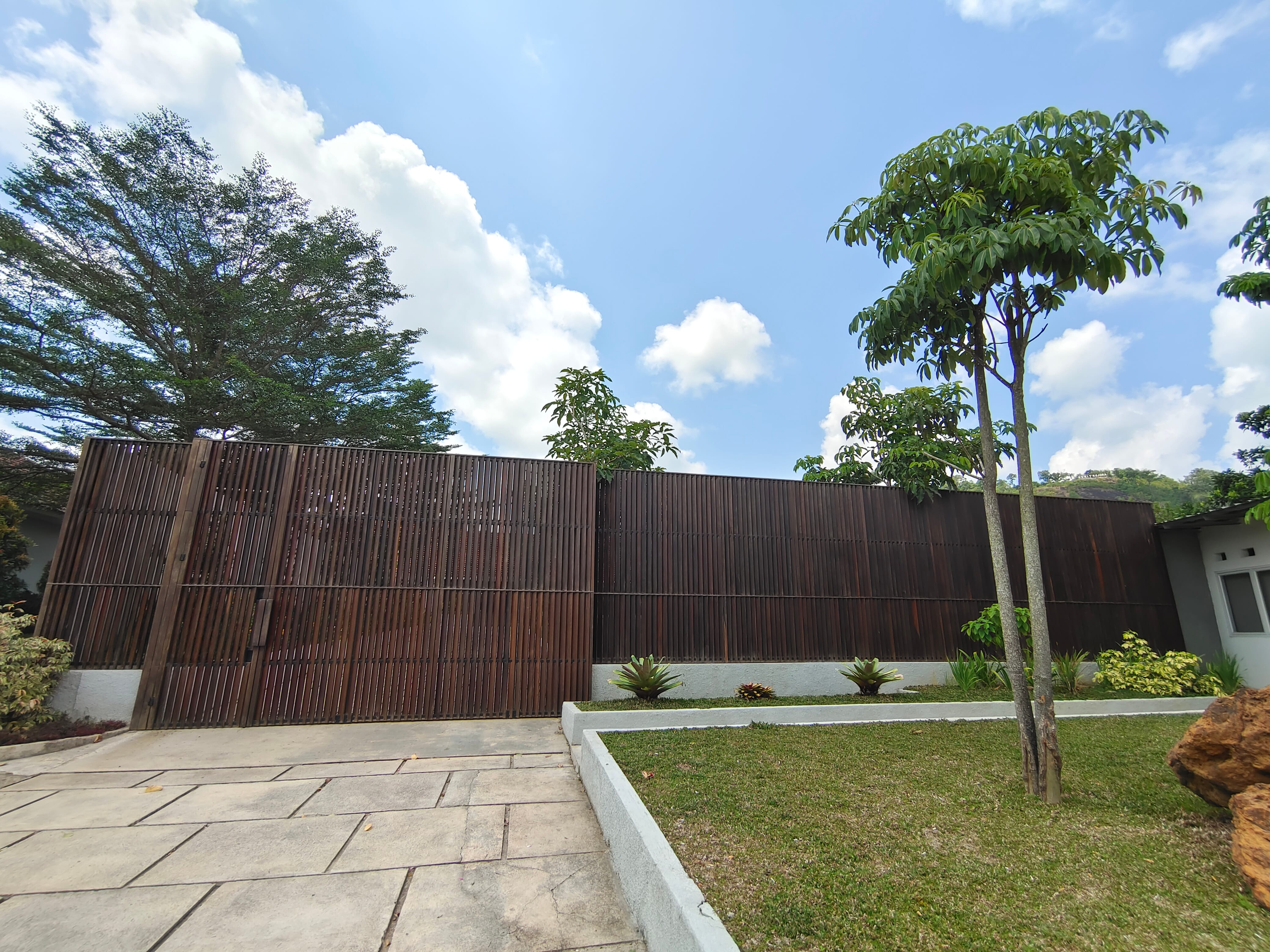 Full-length exterior kisi-kisi fence wall and sliding gate at Kowi Bangka residence by Reywood Indonesia